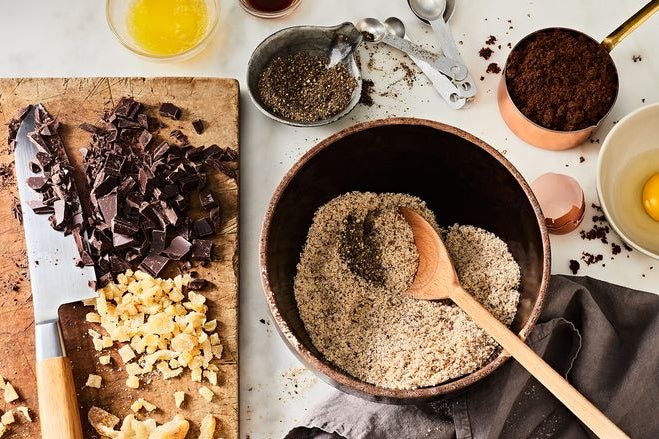 An array of cooking ingredients sits on a table, including freshly cut chunks of chocolate.